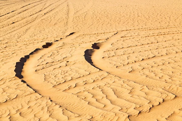 Пустынная трасса некоторых машин в песке и направление движения — стоковое фото