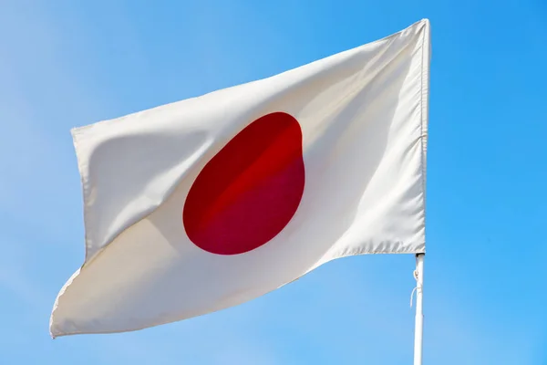 Japanb acenando bandeira no céu azul bcolor e onda — Fotografia de Stock