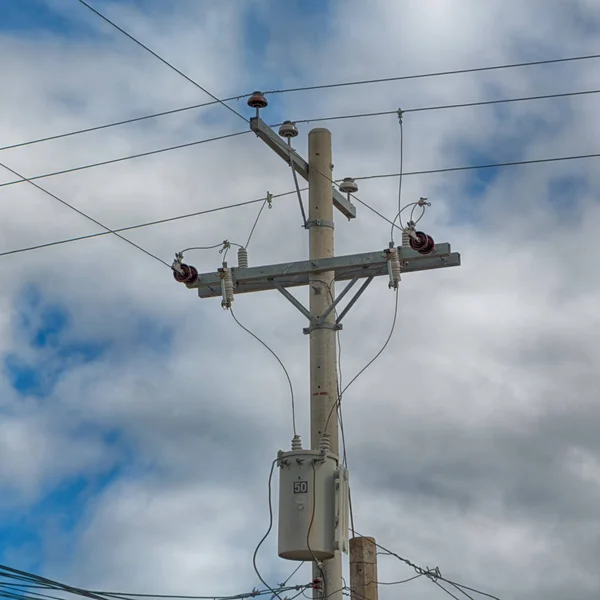 Trafo ve tel bulutlu gökyüzü ile bir elektrik direği — Stok fotoğraf