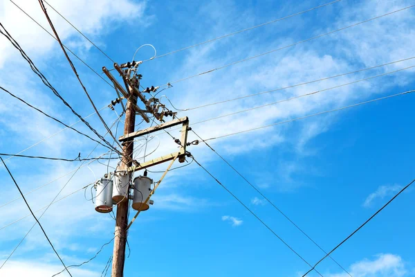 Trafo ve tel bulutlu gökyüzü ile bir elektrik direği — Stok fotoğraf