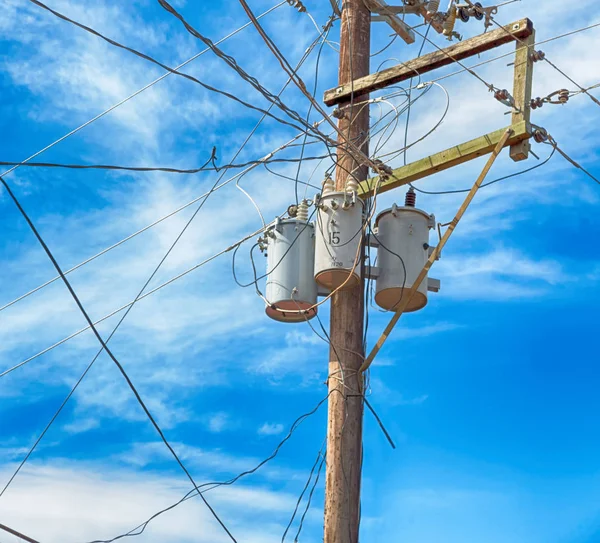 Trafo ve tel bulutlu gökyüzü ile bir elektrik direği — Stok fotoğraf