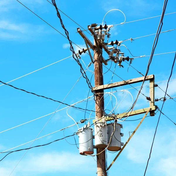 Trafo ve tel bulutlu gökyüzü ile bir elektrik direği — Stok fotoğraf