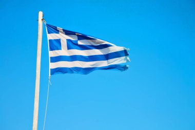 mavi gökyüzünde ve bayrak direğine Yunanistan bayrağı sallayarak