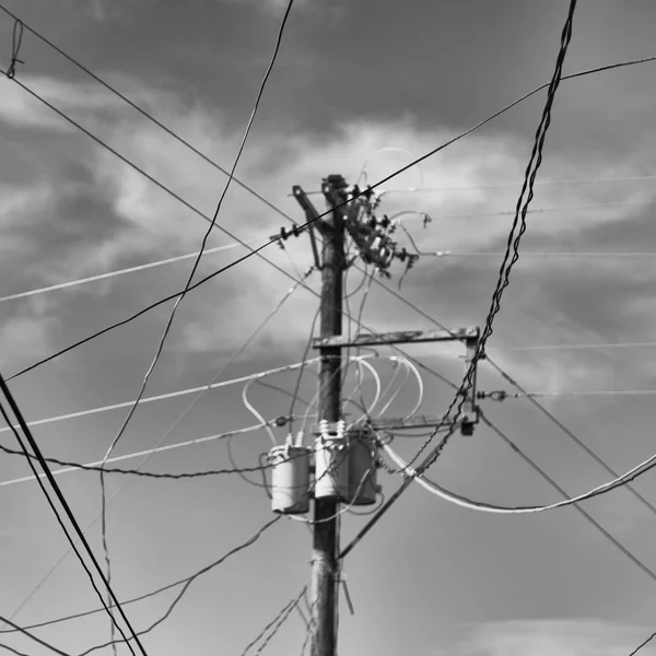 Trafo ve tel bulutlu gökyüzü ile bir elektrik direği — Stok fotoğraf