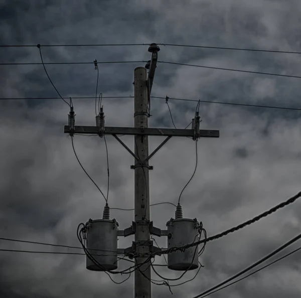 Un poteau électrique avec transformateur et fil le ciel nuageux — Photo