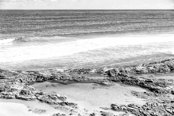 Pláž poblíž skal v vlny oceánu — Stock fotografie