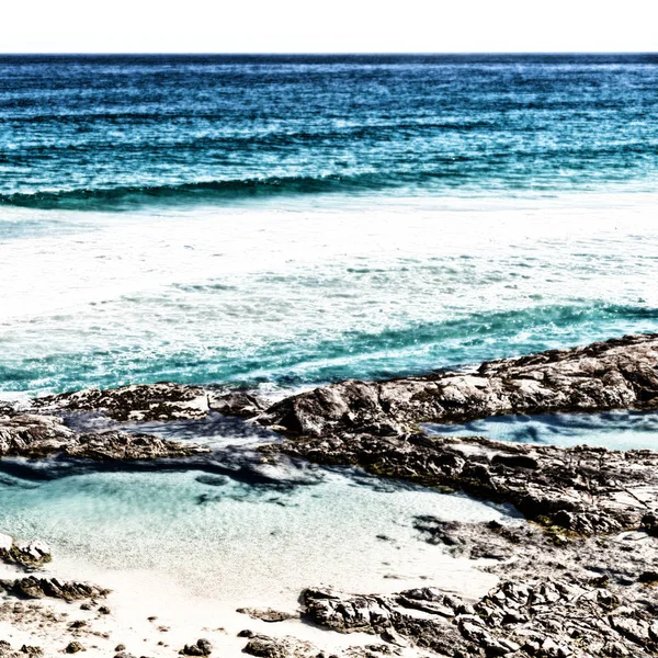 Pláž poblíž skal v vlny oceánu — Stock fotografie