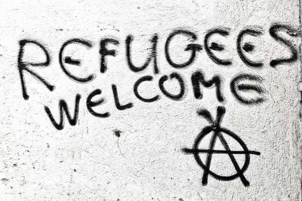 Die Sprühfarbe in der Wand mit Flüchtlingen willkommen — Stockfoto
