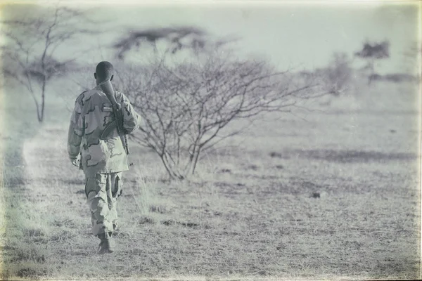 En svart soldat och bössan ser gränsen — Stockfoto