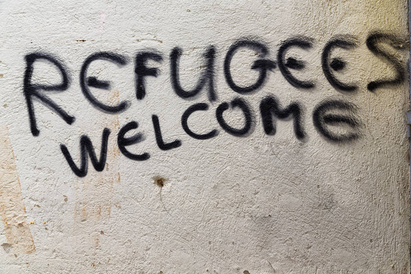 the spray paint in the wall with refugees welcome