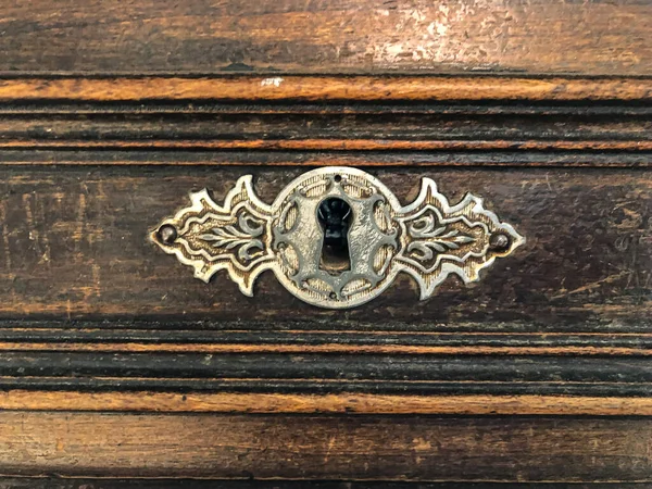 Antique keyhole in a rare chest. Dark wooden surface of an old desk. Oak planks with aged effect. Antique furniture texture.Wooden tabletop with scratches and stains. — Stock Photo, Image