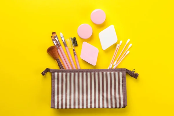 makeup kit. Female makeup brushes in a cosmetic bag on a yellow bright background. women things. top view