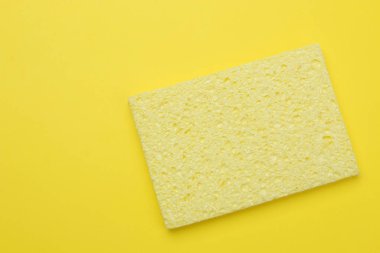 Minimalizm kavramı. Sarı bir arka planda bulaşık yıkamak için sarı bir sünger. Üst Manzara. metin için yer