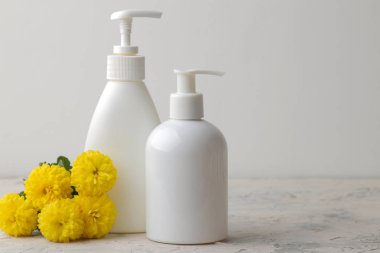 Çeşitli kişisel bakım ürünleri. Yüz kremi, sabun, beyaz arka planda sarı çiçekler. spa