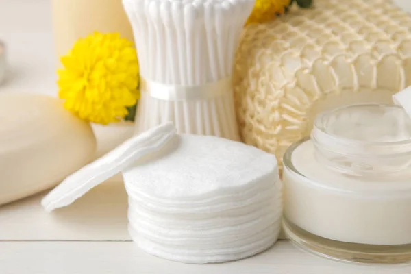 Various personal care products. Cotton pads close-up and sticks and yellow flowers on a white background