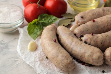 Çiğ sosisler kızartma, sarımsak, domates, yağ ve hafif arkaplan için malzemeler hazırlandı.