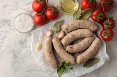Çiğ sosisler kızartılmaya ve hafif arka planda pişirme, sarımsak, domates ve yağ için malzemeler hazırlandı. en üstteki görünüm