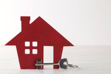 Ev satın alma konsepti. Beyaz arka planda küçük dekoratif ev ve anahtarlar