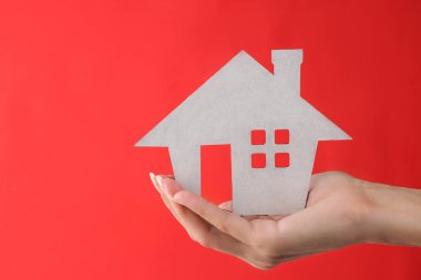 Ev satın alma konsepti. Kırmızı arka planda küçük dekoratif beyaz ev