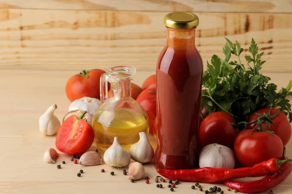 Red sauce in a bottle and ingredients for cooking, butter. tomatoes, peppers, garlic on a natural wooden background