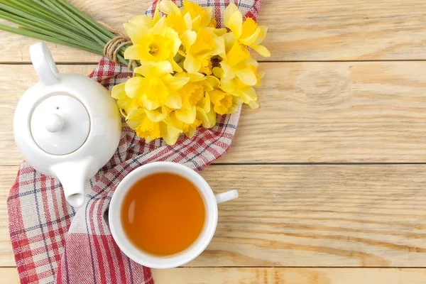 春天的花朵 黄色的水仙花和一杯茶在一个天然的木制背景 案文的位置 — 图库照片