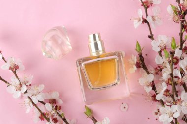 Çiçek açan dal. Pembe arka planda bahar çiçekleri ve parfüm şişesi. en üstteki görünüm.