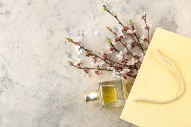 Çiçek açan dal. Bahar çiçekleri ve parfüm şişesi açık beton bir masada hediye çantasının içinde. en üstteki görünüm