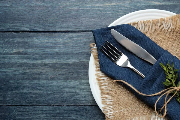 餐桌布置 蓝色餐巾上的盘子和餐具 蓝色木制桌子上的叉子和刀 顶部视图 — 图库照片