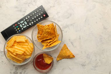 Patlamış mısır, çeşitli atıştırmalıklar ve hafif beton bir masada uzaktan kumanda. Evde film ya da video izleme kavramı. en üstteki görünüm