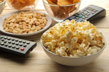 Patlamış mısır, çeşitli atıştırmalıklar ve televizyon kumandası. Evde film veya video izleme kavramı.