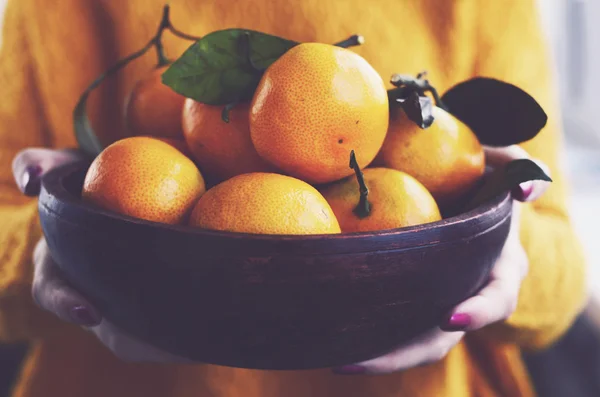 新鮮なクレメンタインと椀を保持しているオレンジ色のニット プルオーバーの女性 — ストック写真