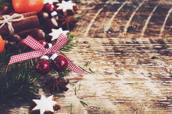 Sfondo natalizio con stelle di pan di zenzero, ramoscelli di abete, palline rosse, bastoncini di cannella e mandarini freschi su sfondo rustico — Foto Stock