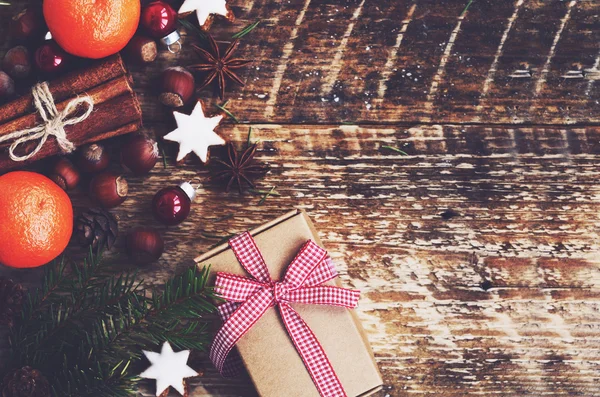Vinter bakgrund - presentbox med band och rosett, fir tree kvistar, kryddor och cookies med copyspace på trä bakgrund — Stockfoto