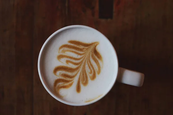 Šálek cappuccino na hnědý dřevěný stůl — Stock fotografie