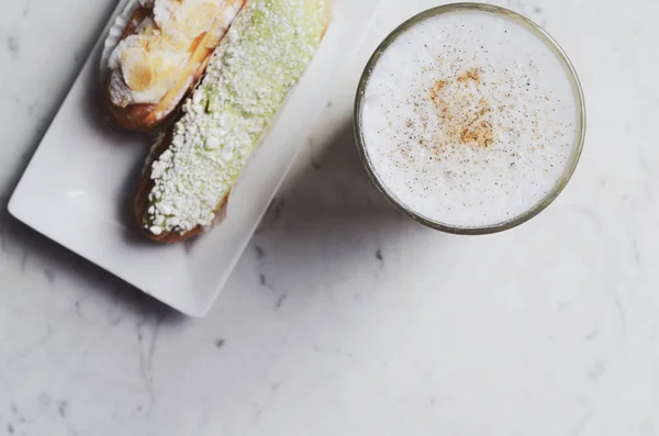 Latte en heerlijke eclairs met kopie ruimte op marmeren achtergrond — Stockfoto