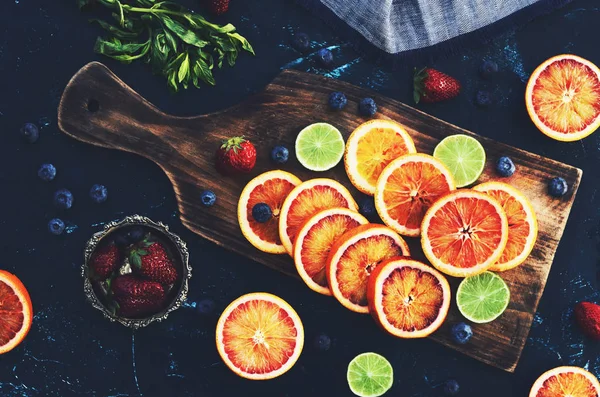 Mix van diverse citrus vruchten - rode sinaasappelen en limoenen op houten snijplank — Stockfoto