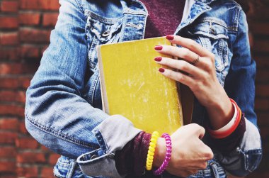 Kitap onun elinde tutan kot ceketli genç öğrenci