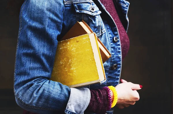 Jonge vrouw in jeans slijtage met oude boeken in haar hand — Stockfoto