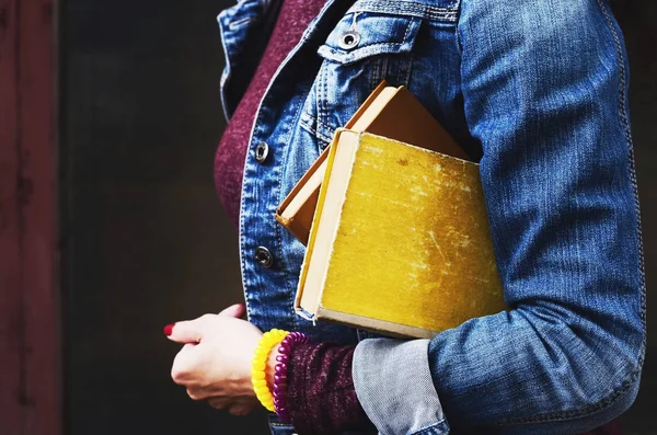Yığın kitap onun elinde tutan kot ceketli genç kadın