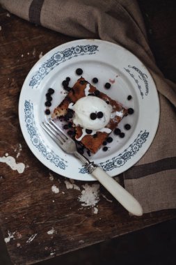 Ev yapımı yabanmersinli turta, vanilyalı dondurma, ahşap masa, üst manzara.