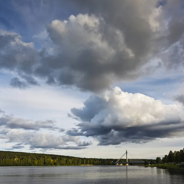 O céu com nuvens e uma ponte sobre o rio. Finlândia — Fotografia de Stock