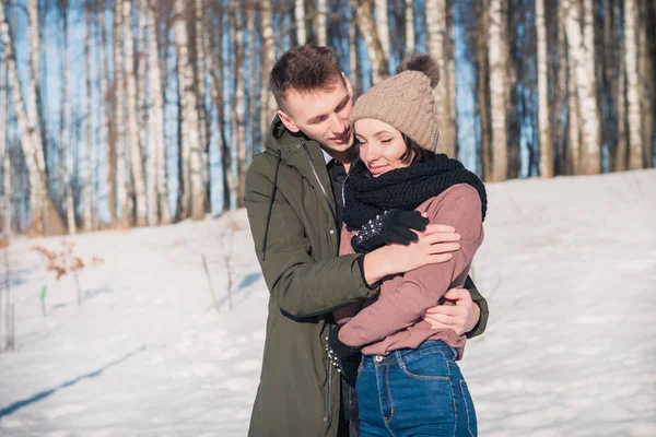 晴れた日には冬の公園で恋に美しい若いカップル 男は彼の腕の中で彼の最愛の女の子を暖める — ストック写真