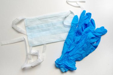 Tıbbi tek kullanımlık maske ve beyaz arka planda mavi eldivenler. Kişisel koruma ekipmanları.
