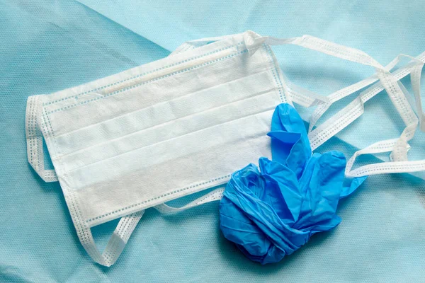 Medical disposable mask and blue gloves on a non-woven material for the manufacture of medical clothing. Personal protective equipment