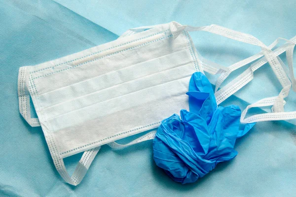 Tıbbi giysi üretimi için örülmemiş bir malzemede tıbbi tek kullanımlık maske ve mavi eldivenler. Kişisel koruma ekipmanları