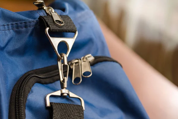 Karabinalı, kemerli ve fermuarlı mavi spor çantalı.