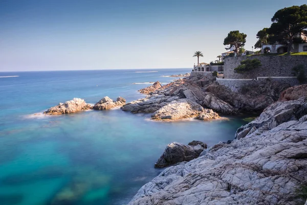Platja d'Aro zümrüt suların mavi bir gökyüzü altında bir Akdeniz kayalık kıyılarının uzun pozlama