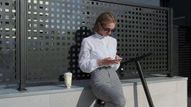 Cep telefonu ve scooterı olan bir iş kadını.