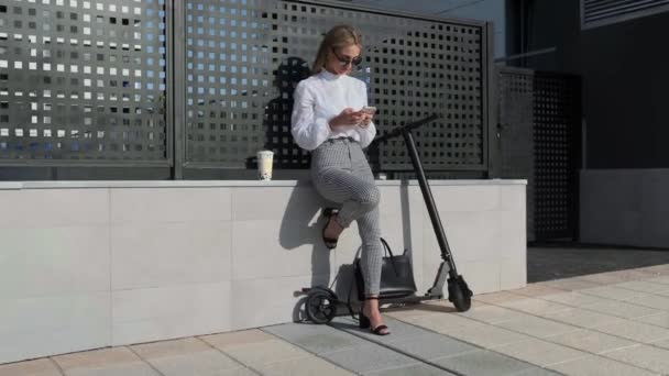 Donna d'affari con cellulare e il suo scooter accanto — Video Stock