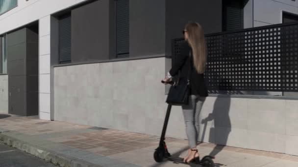Nierozpoznawalna kobieta podróżująca na skuterze elektrycznym po chodniku — Wideo stockowe